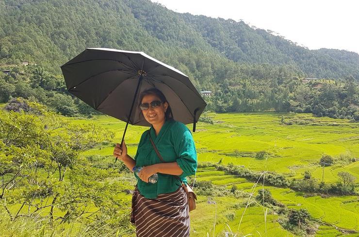 Lächelnde Frau mit Sonnenschirm im grünen Punaka-Tal