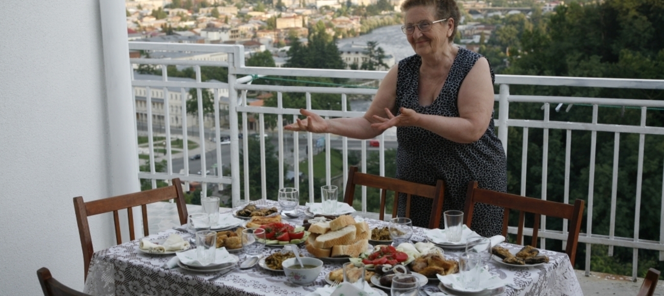 Gastgeberin in Georgien vor gedecktem Tisch.